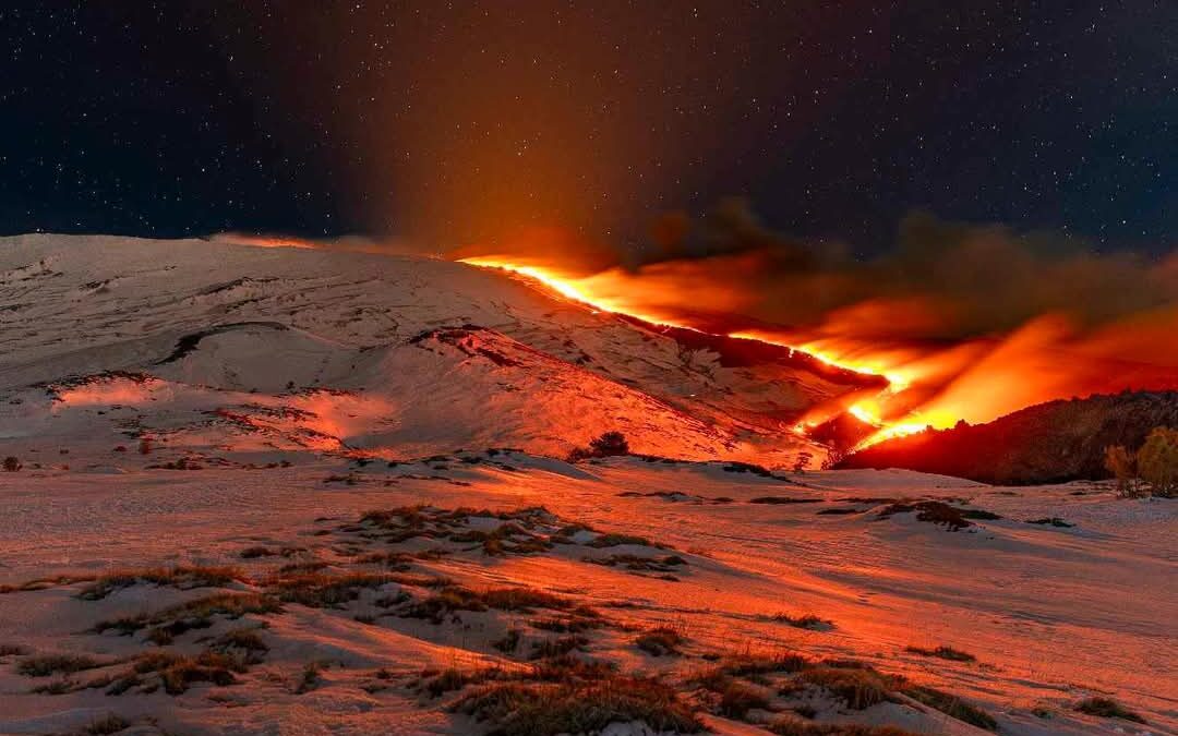 Sull’ETNA, spettacolare colata lavica tra la neve bianca, il bagliore rosso e un immenso cielo stellato